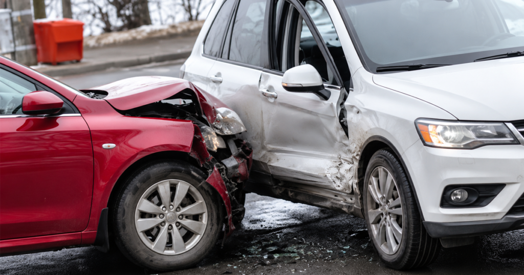 Red car collided with a white SUV on a wet road, showing visible crash damage on both vehicles.